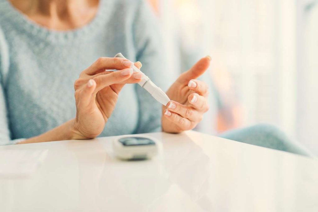 mulher medindo glicose e alertando os sintomas do diabetes