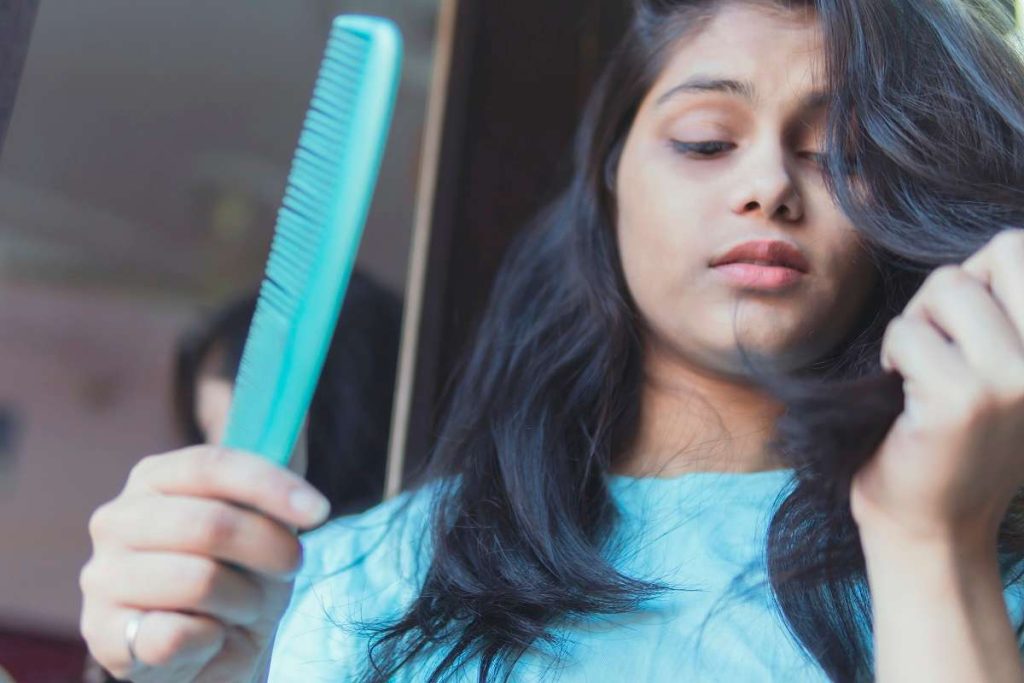 mulher com queda de cabelo recolhe fios do pente