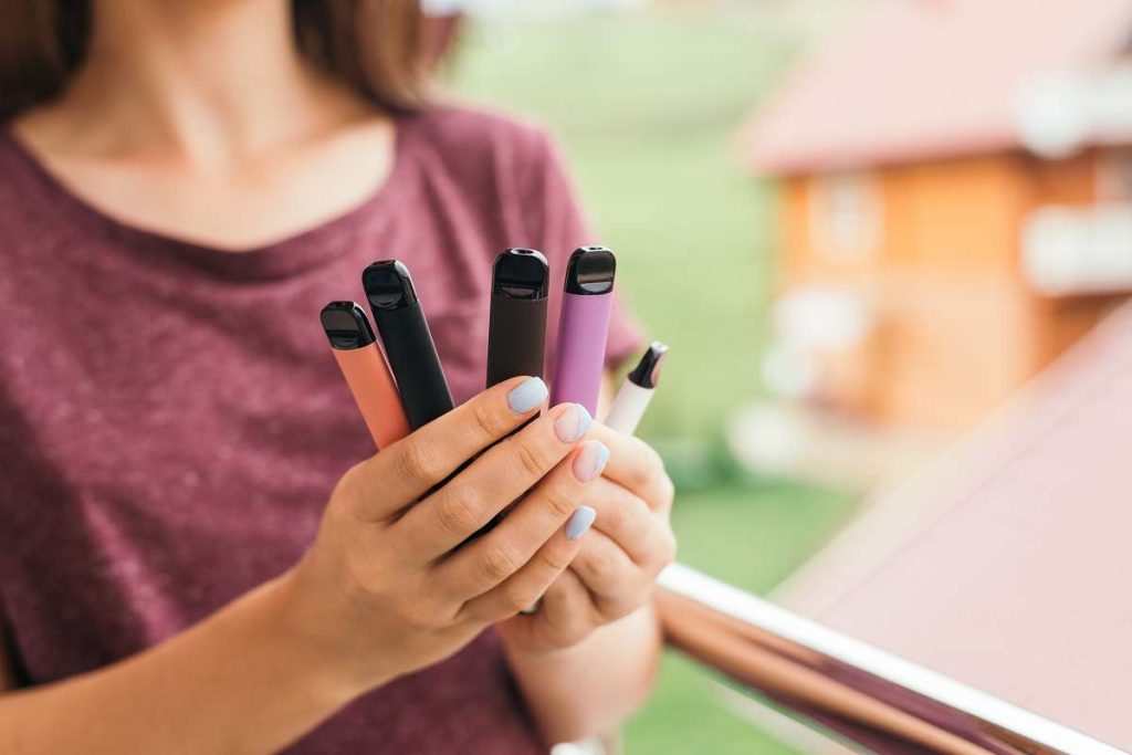 mulher segurando vários cigarros eletrônicos