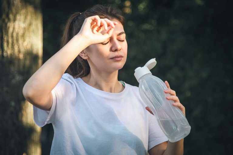 mulher com pressão baixa no calor toma água