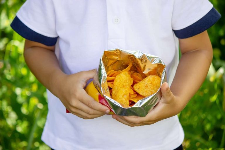 criança comendo salgadinhos ultraprocessados na alimentação